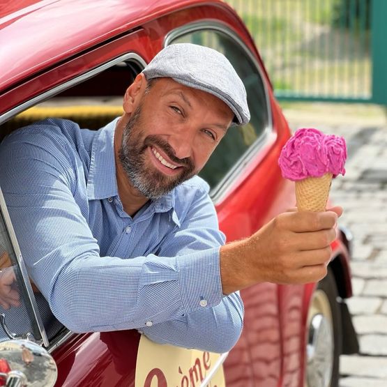 Honza drží u červeného auta Crème de la Crème kornout s růžovým sorbetem z dračího ovoce