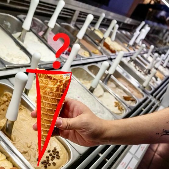 Ruka drží kornout před vitrínou se zmrzlinou a červeným otazníkem